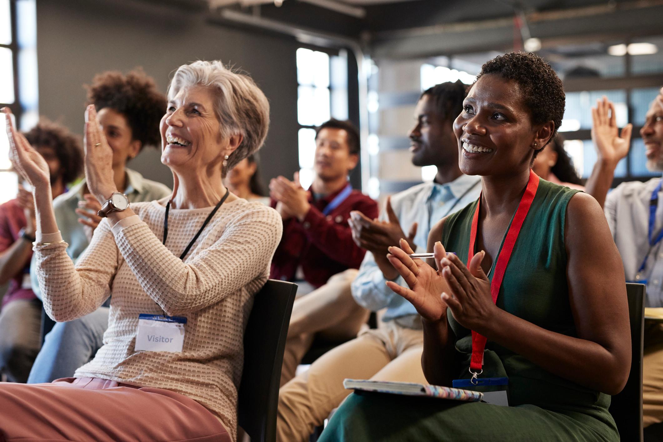 Men and women applauding and smiling at the end of a presentation