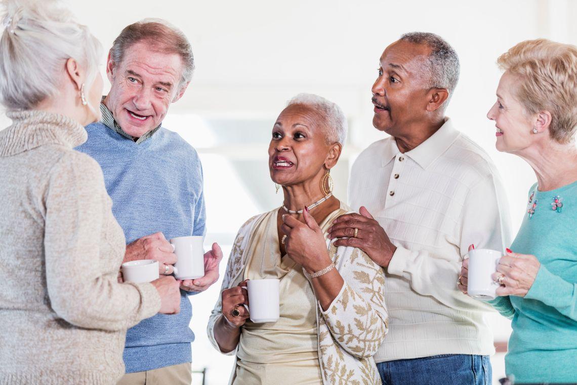 A group of five people holding coffee cups and talking